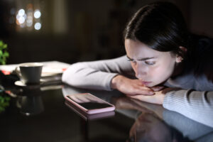 Mulher triste olhando o celular, representando o ghosting econômico e o impacto do endividamento nas relações pessoais.