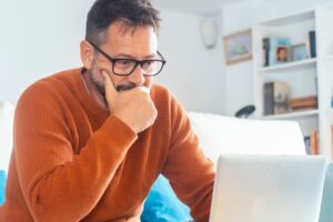 Homem pensativo avaliando se deve vender seu consórcio cancelado ou esperar o sorteio, representando decisão financeira inteligente.