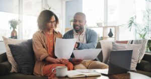 Casal analisando documentos financeiros no notebook como parte do planejamento financeiro