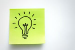 Ilustração de lâmpada acesa sobre nota verde, simbolizando o momento de tomar a decisão certa de vender a cota de consórcio.