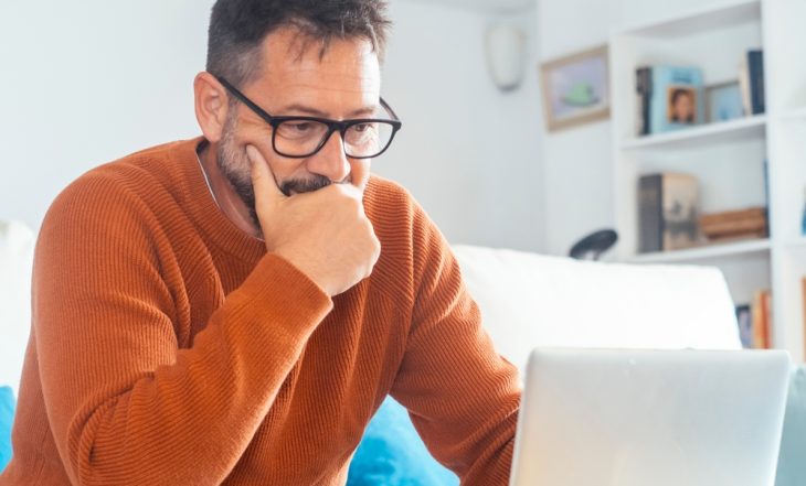 Homem pensativo avaliando se deve vender seu consórcio cancelado ou esperar o sorteio, representando decisão financeira inteligente.